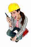 Female construction worker yelling into a walkie-talkie