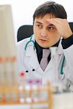 Concerned medical doctor working on computer at office