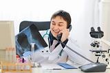 Smiling medical doctor holding patients roentgen and speaking phone