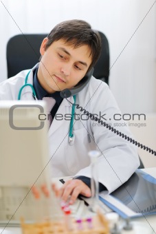 Busy medical speaking phone and working on computer