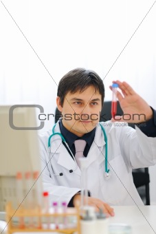 Medical doctor checking tube with blood sample