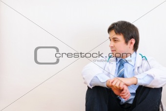 Medical doctor sitting on floor and looking on corner