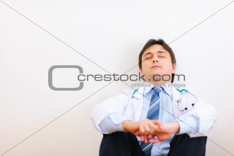 Tired medical doctor sitting on floor and relaxing