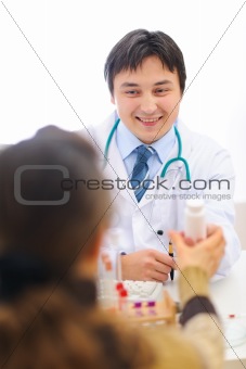 Smiling medical doctor giving pills to patient
