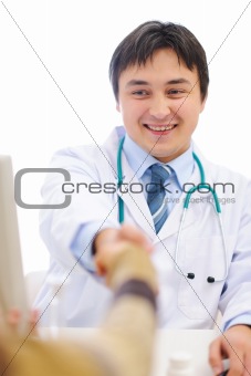 Smiling medical shaking patients hand