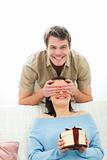 Young man closing eye to girlfriend to present gift