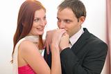 Young man in suit kissing hands of red hair woman in evening dress