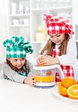 Little girls making fresh orange juice