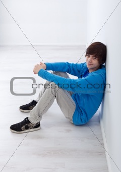Teenager boy sitting by the wall