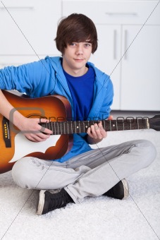 Young teenager boy playing the guitar