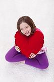 Young girl with large red heart pillow