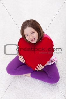 Young girl with large red heart pillow