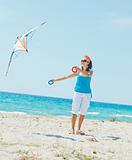 Woman on beach playing with a colorful kite