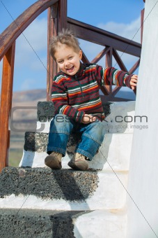 Happy little boy sitting on stairs