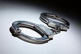 Abstract Pair of Handcuffs Under Spot Light on Gradated Background.