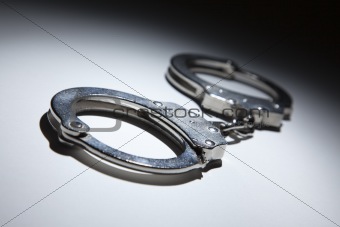 Abstract Pair of Handcuffs Under Spot Light on Gradated Background.