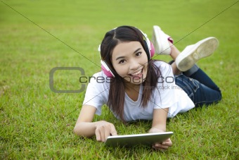 young woman using tablet pc on the grass
