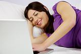 attractive woman reads her laptop laying in bed