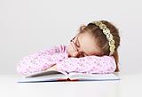 Tired schoolgirl sleeping on book