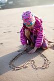 Girl drawing a heart in sand