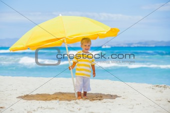 Boy with big umbrella on tropical beach