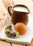 Ceramic jug with milk and eggs on a wooden table , rustic style
