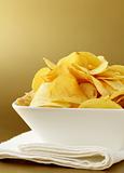 potato chips in a white bowl on a gold background