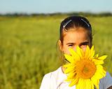 Portrait of a cute little girl hiding behind sunflower 