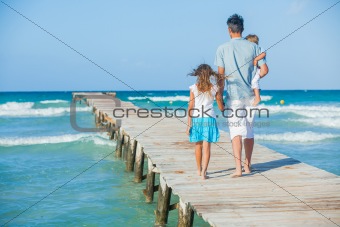 Family of three on jetty by the ocean