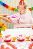 Surprised baby receiving present on first birthday