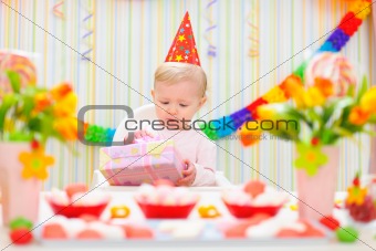 Surprised baby looking on present on first birthday