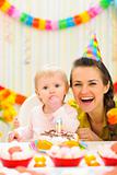 Portrait of mother with baby enjoying first birthday cake