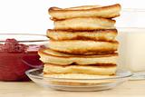 heap of pancakes with bowl of strawberry jam