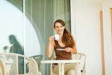 Smiling girl having cup of coffee at terrace