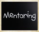 The word "Mentoring" handwritten with white chalk on a blackboar