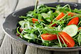 salad with arugula and cherry tomatoes on black vintage plate