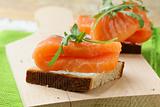 Sandwich with smoked salmon and arugula on a wooden board