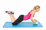 Young blond woman doing pushups on medicine ball, lower position
