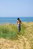 Muscular male model on the beach walking in a corn field 