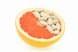Close up of red grapefruit and pills isolated - vitamin concept