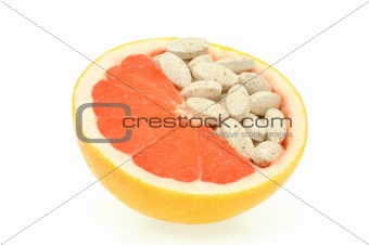 Close up of red grapefruit and pills isolated - vitamin concept