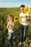 Portrait of two cute little girls with sunflowers 
