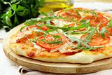 Margarita pizza with tomatoes and with arugula,  on the board