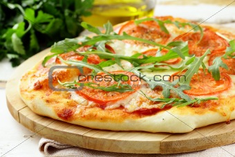 Margarita pizza with tomatoes and with arugula,  on the board