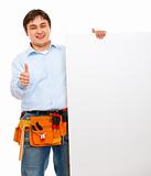 Construction worker holding blank billboard and showing thumbs up