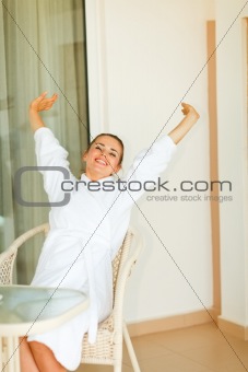 Woman in bathrobe stretching on terrace