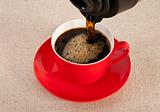 Black expresso in a red coffee cup on canvas background