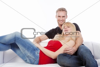 young couple sitting on sofa smiling, embracing  