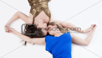 two young women lying on the floor, holding hands - view from above