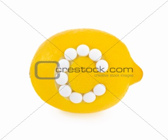 Lemon with vitamin c pills over white background - concept